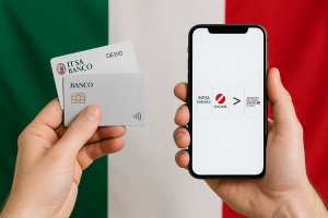 Una persona tiene due carte bancarie italiane nella mano sinistra e uno smartphone nella mano destra, con la bandiera italiana sfocata sullo sfondo. Le carte mostrano elementi tecnologici come il simbolo del chip e del pagamento di prossimità, mentre il cellulare mostra un confronto tra le banche italiane.