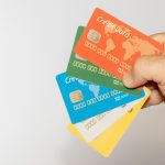 Mano che tiene diverse carte di credito colorate, simbolo della varietà di opzioni di pagamento disponibili per acquisti con carte di debito, credito e revolving.