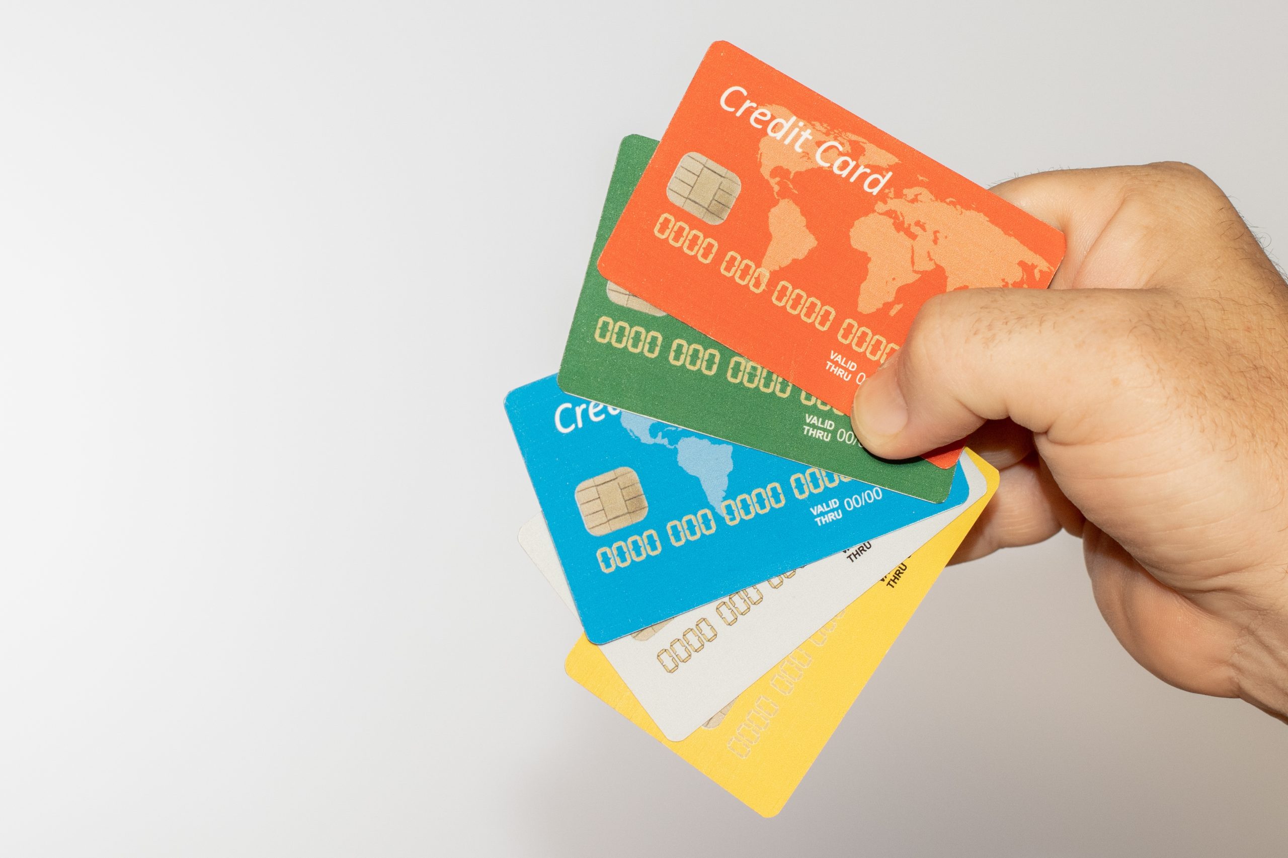 Mano che tiene diverse carte di credito colorate, simbolo della varietà di opzioni di pagamento disponibili per acquisti con carte di debito, credito e revolving.