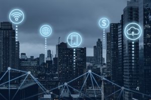 Veduta urbana di una grande città al tramonto con grattacieli moderni, sovrapposta a icone digitali luminose che rappresentano connessioni Wi-Fi, rete globale, smartphone, denaro e cloud. Le linee connesse tra gli edifici illustrano un'infrastruttura tecnologica avanzata, simbolo dello sviluppo digitale urbano. L'immagine evoca l'ecosistema dell'innovazione e della digitalizzazione finanziaria, contesto in cui la Fintech in Italia sta emergendo con soluzioni smart per la gestione economica e bancaria attraverso piattaforme integrate e connesse.
