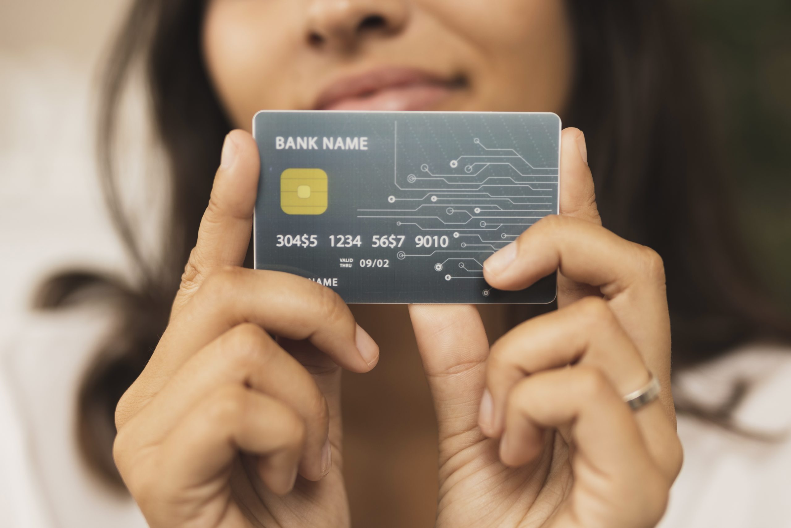 Una donna tiene in mano una carta di credito con design futuristico, chip dorato e circuito stampato visibile sul lato destro. Il nome della banca è generico e i numeri della carta sono parzialmente fittizi. L'immagine rappresenta l'evoluzione digitale dei pagamenti e il ruolo crescente delle carte di credito co-branded nel semplificare l'esperienza finanziaria personalizzata.
