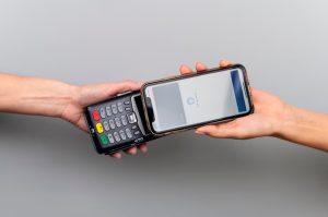 Pagamento contactless con carta di debito intelligente tramite smartphone su terminale POS, evidenziando l'uso di tecnologie moderne per transazioni rapide e sicure.